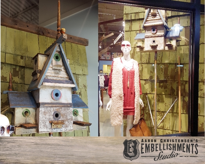 A faux vintage birdhouse created from reclaimed wood and oddities by Aaron Christensen.  The piece becomes a focal point in a retail boutique's store window.